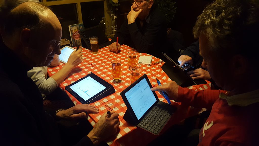 Een groep mensen aan tafel die tablets gebruiken.