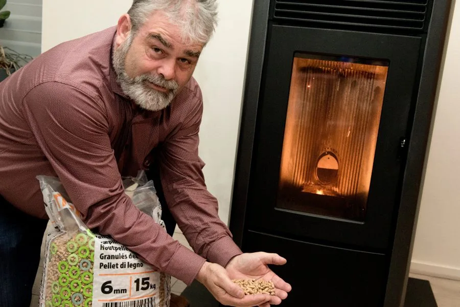 Een man knielt voor een houtkachel.