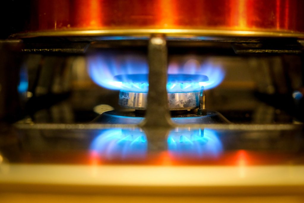 Een close-up van een gasfornuis met blauwe vlammen.