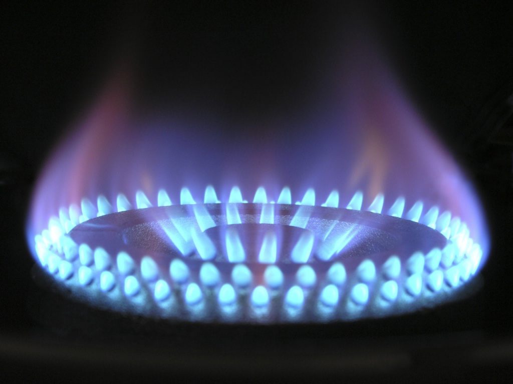 Een close-up van een gasfornuis met blauwe vlammen.